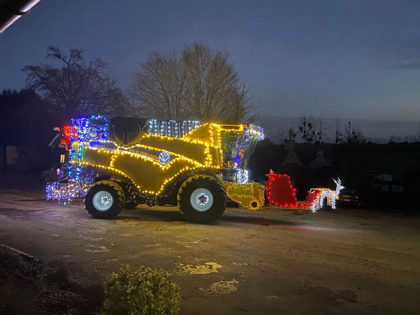 La moissonneuse-batteuse New Holland illuminée de guirlandes pour Noël, avec un traîneau et un renne lumineux