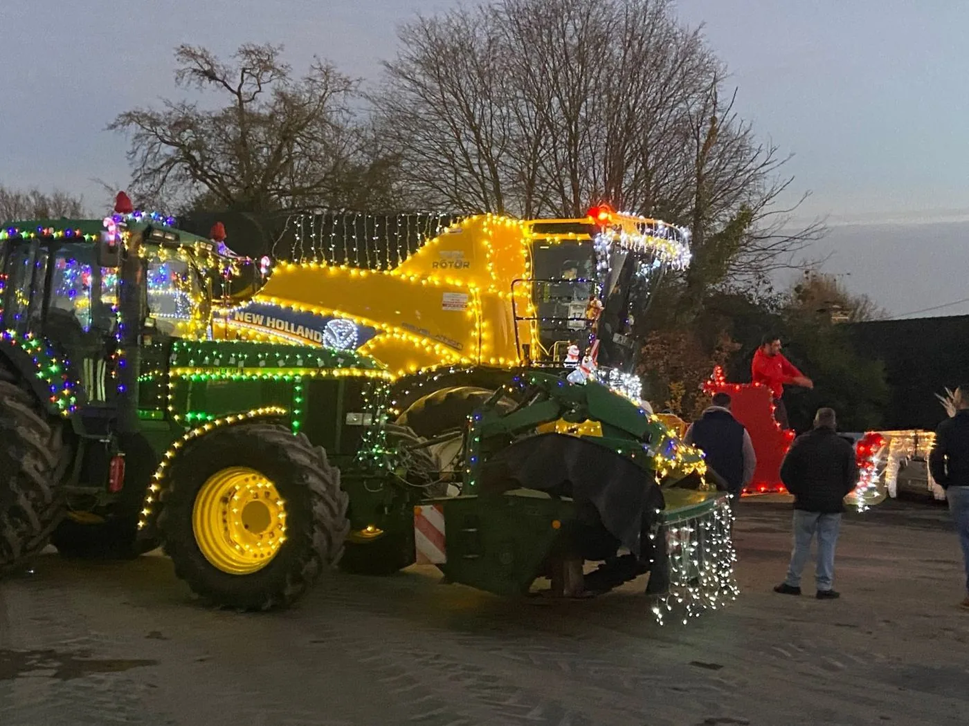 Un tracteur John Deere et la moissonneuse New Holland couverts de guirlandes lumineuses